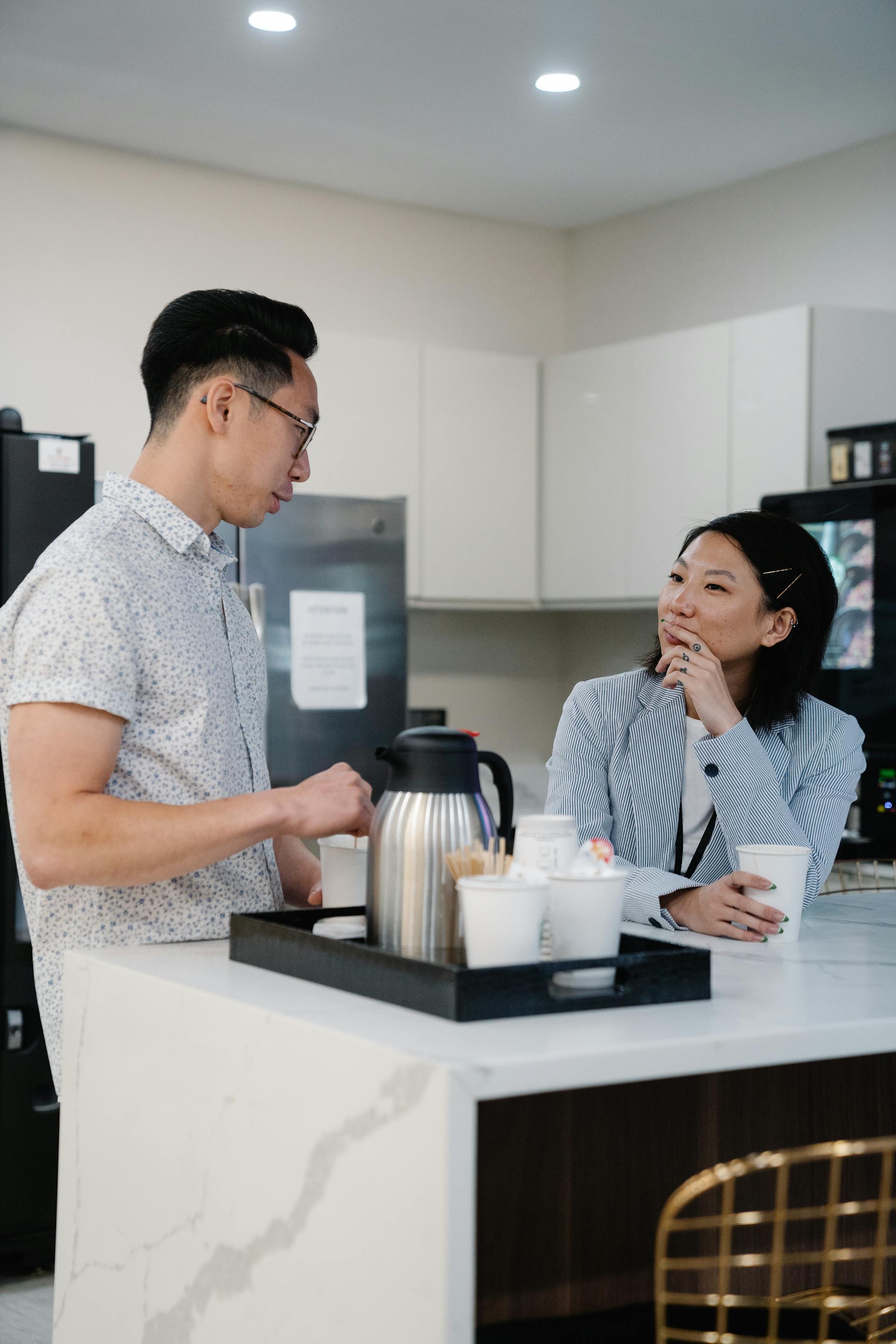 Coworkers enjoying coffee, chatting at the office kitchenette